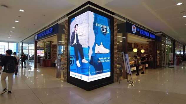 an led screen featuring a man and a white shoe inside a mall