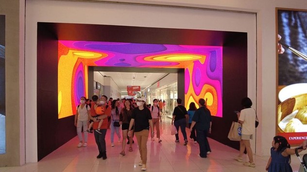a shot of people walking inside a mall behind an led screen